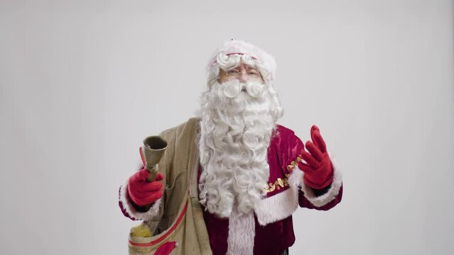 santa claus with bag and ring bell portrait against white background talking and making hand gestures