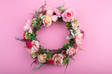 Colorful artificial flowers wreath isolated on pink background.