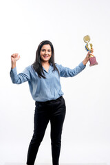 Indian woman employee giving expression with winning trophy on white background.