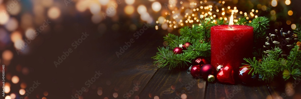 Wall mural christmas background - red burning advent candle with fir branches on wooden board - magic bokeh lig