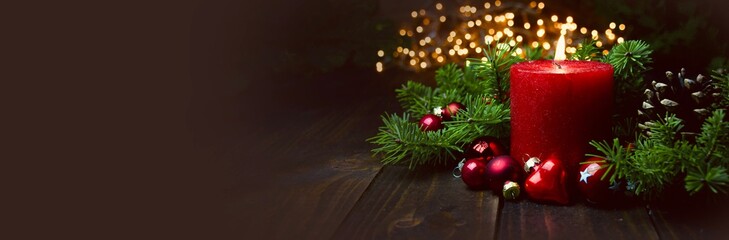 Red burning Advent Candle with Christmas ball and tree branches on wood - Christmas background banner, panorama, header with copy space - xmas card - 543855482