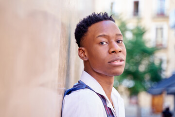 portrait of a young African posing against a wall with a serious look on his face