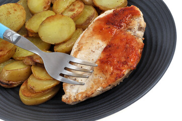 Assiette avec un blanc de poulet et des pommes de terre sautées en gros plan sur fond blanc