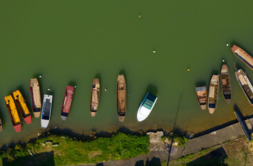 Group of small boats on the bank of the green river - aerial drone photo