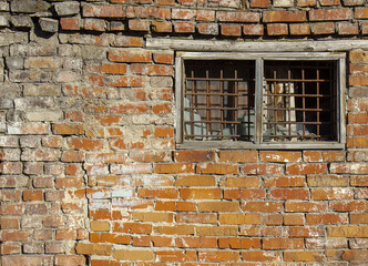 Fototapeta na wymiar A window with a lattice of an old village room for the temporary detention of criminals.