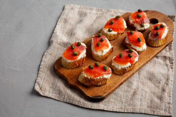 Homemade Lox And Cream Cheese Crostini on a wooden board, side view. Copy space.