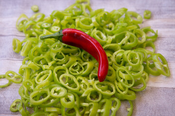 Hot red chili peppers on a background of green pepper pieces. Healthy food concept.