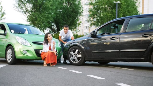 A man and a woman driver are arguing at two colliding cars.
