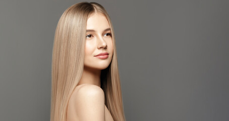 Hair care model.Beauty young woman with long healthy hair posing against grey background. Beauty...