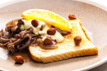 beef mixture with sauce, hazelnuts and orange served with roasted toast