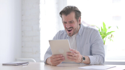 Young Man Reacting to Loss on Tablet in Office