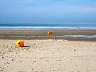 Beach with yellow buoys at low tide of Fort Mahon, a commune in the Somme department in Hauts-de-France in northern France. 