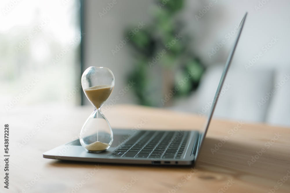 Poster Hourglass on a laptop computer. Concept for time management and counting down to a deadline. concept of time management, business schedule, and deadline