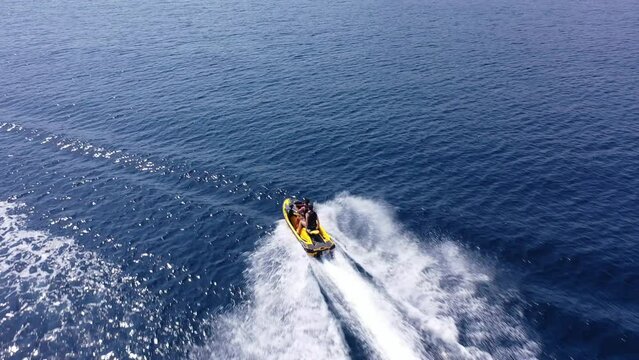 Aerial drone video of jet ski watercraft operated by stunt man speeding in deep blue open ocean sea
