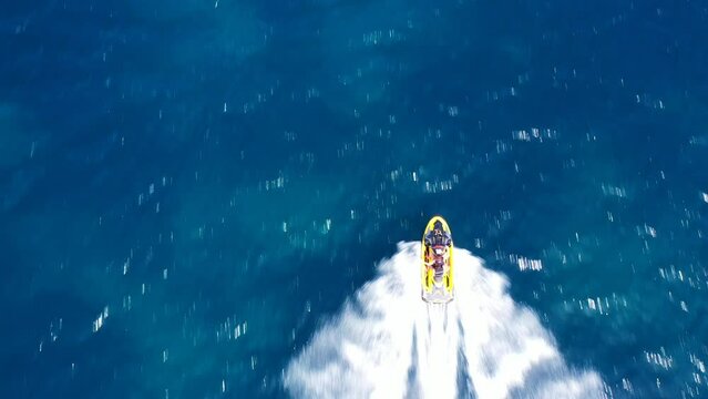 Aerial drone video of jet ski watercraft operated by stunt man speeding in deep blue open ocean sea