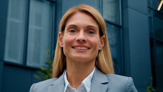 Headshot successful confident business woman leader professional manager standing outdoors looking at camera beautiful smiling caucasian businesswoman corporate employee posing near office building