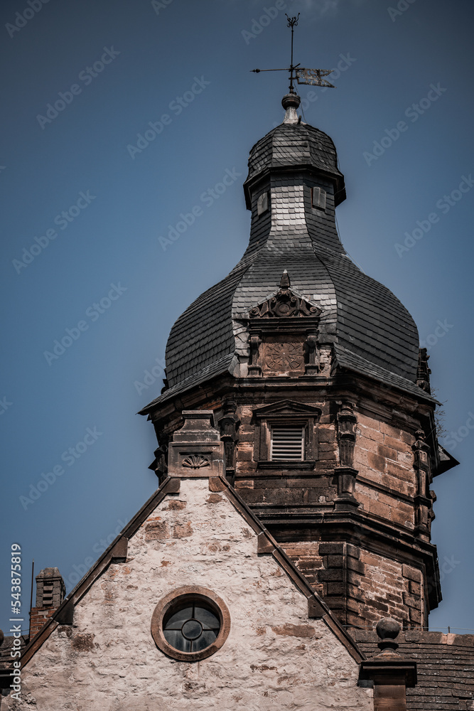 Aufkleber a tall building with a clock on the top of it's tower and a weather vane on top.