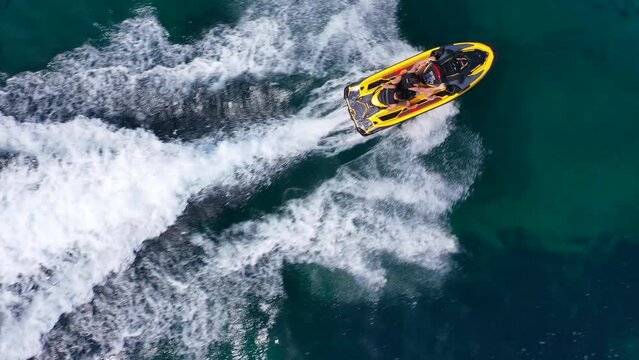 Aerial drone video of jet ski watercraft operated by stunt man speeding in deep blue open ocean sea
