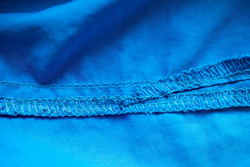 Overlock seam on blue fabric. Textured cloth background. Place for text. Flatley. 