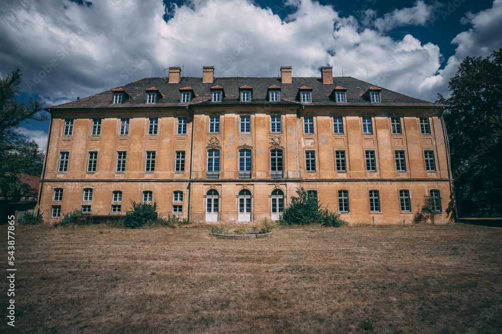 Poster a large building with a lot of windows and a sky background with clouds in the sky above it and a gr