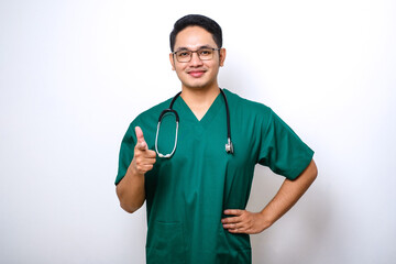 Confident smiling asian male doctor, nurse in scrubs pointing finger at camera, inviting for...