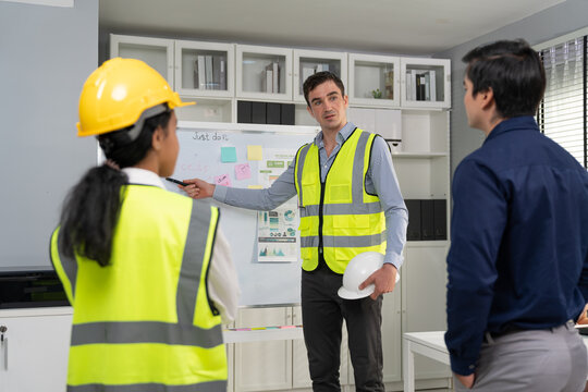 Engineer leader man presentation project and strategy plan to success on whiteboard with businessman corporate in meeting room at construction site office