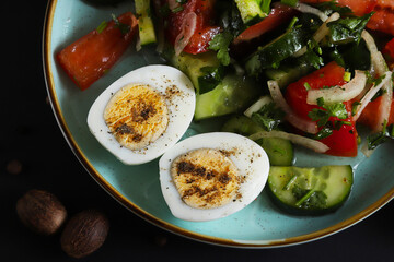 Cut boiled egg on a plate with a summer salad of cucumbers and tomatoes. Shallow depth of field