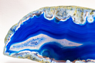 Vibrant deep blue and semi-transparent agate geode slice crystal, banded chalcedony stone isolated on a white background surface with lots of detail. Abstract blue crystal wallpaper