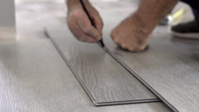 Male hands marking with a pencil a sheet of vinyl flooring