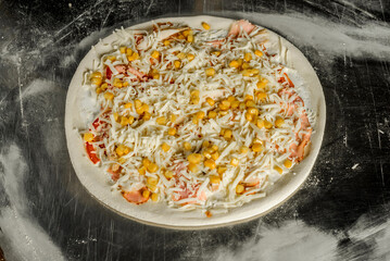 dough, flour, pizza topping, sauce and chef's hands in black gloves on the table