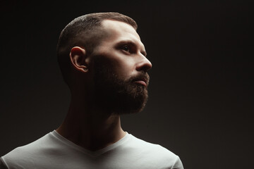 Male beauty concept. Profile portrait of proud charismatic active 30-year-old man posing over dark...