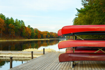 overcast day with rack of red canoes on dock of Old Ausable Channel river in the Pinery Provincial Park in the autumn - Powered by Adobe