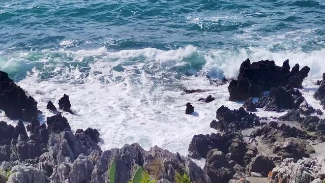 Ocean Waves Collides with Large Rocks Breaking on the Edge of Rocks on the Tropical Coast of Diamante, in Calabria, Illuminated by the Italian Sun.