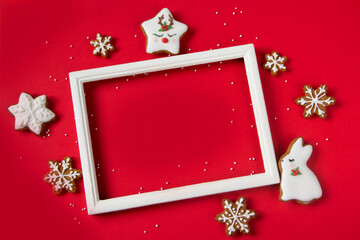 Christmas frame with gingerbread cookies on red background. Christmas cookies-deer, bunny and...