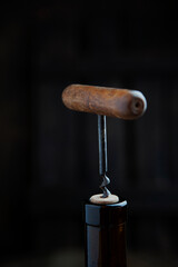 Corkscrew and cork. A wooden corkscrew is stuck in the cork. The neck of bottle. Vertical photo....
