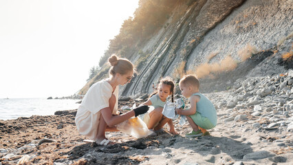 Little siblings helping mother to collect garbage on sea beach in plastic bag. Happy family activists collecting trash. Concept about environmental conservation pollution problems and responsibility.