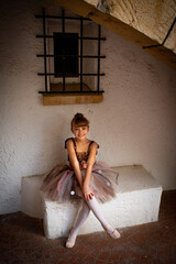 Niña pequeña posando baile ballet frente a una fachada o pared blanca de piedra antigua, con un...