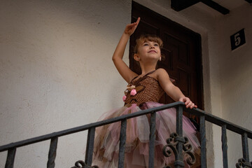 Niña pequeña posando baile ballet frente a una fachada o pared blanca de piedra antigua, con un...