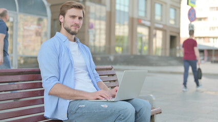 Rejecting Man in Denial While using Laptop Sitting Outdoor on Bench