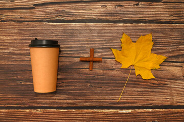 A glass of coffee and a maple leaf on a brown background. Autumn warmth concept.