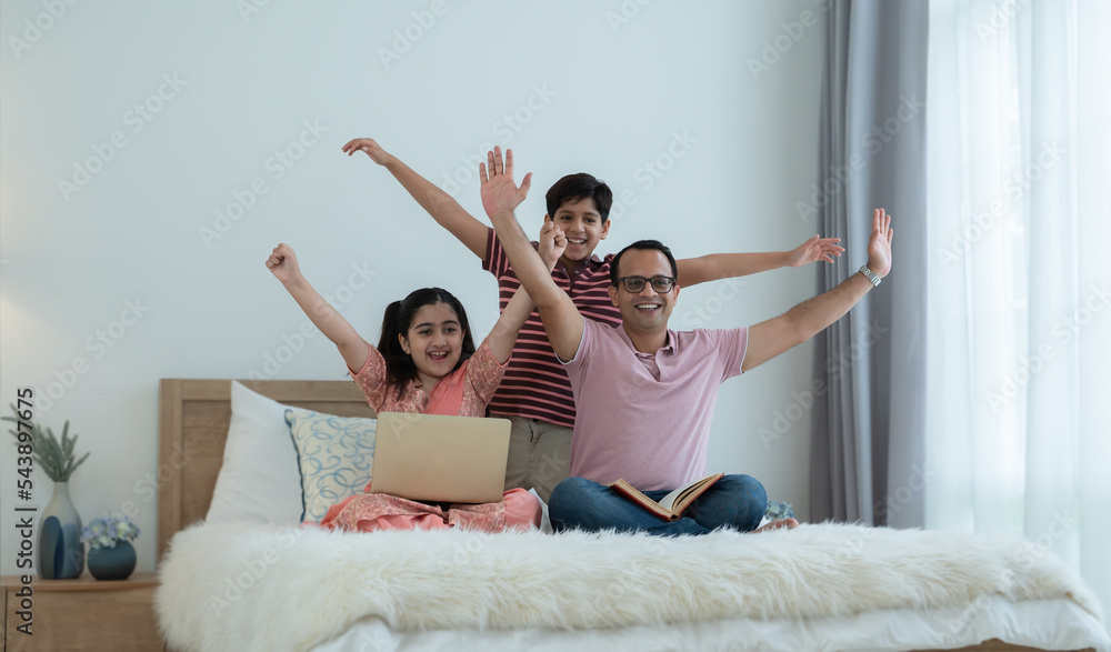 Wall mural cheerful indian family teenage boy son and girl with dad have fun and raising hands up together whil