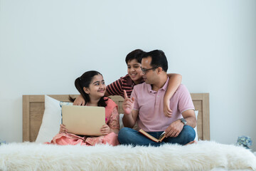 Happy indian family teenage boy son and girl with dad talking, teaching and doing daughter homework...
