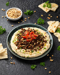 Hummus with spiced ground beef, olive oil, tomatoes and toasted pine nuts