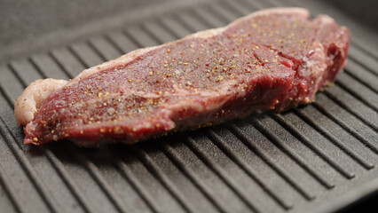 frying new york steak with tongs on grill pan