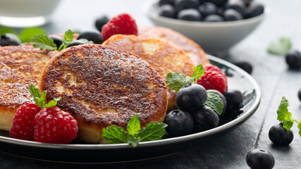 Cottage cheese pancakes served with blueberries, raspberries, strawberry jam and mint leaves, healthy vegetarian protein breakfast