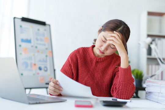 Young Asian business women feel stressed at work when faced with difficult tasks and unsolvable problems I feel aches and pains in my body due to stress while working on my laptop computer.