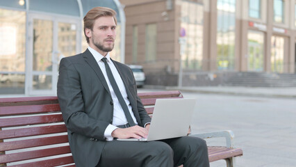 Rejecting Businessman in Denial While using Laptop Sitting Outdoor on Bench