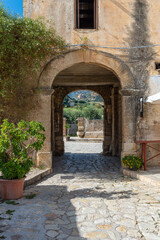 Fototapeta na wymiar Passageway to the picturesque courtyard or baglio with gastronomy in the village Scopello on Sicily. A hamlet of houses clustered around a common courtyard