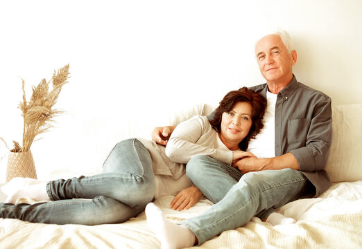 Mature 60 Year Old Couple Hugging While Laying On The Bed In The Bedroom.