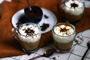 Small mugs with a three-layer coffee-caramel dessert. Delicious pudding in glass cups.